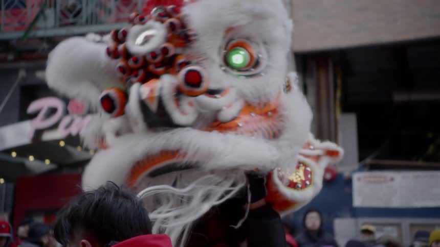 A person in a dragon costume dances in a parade
