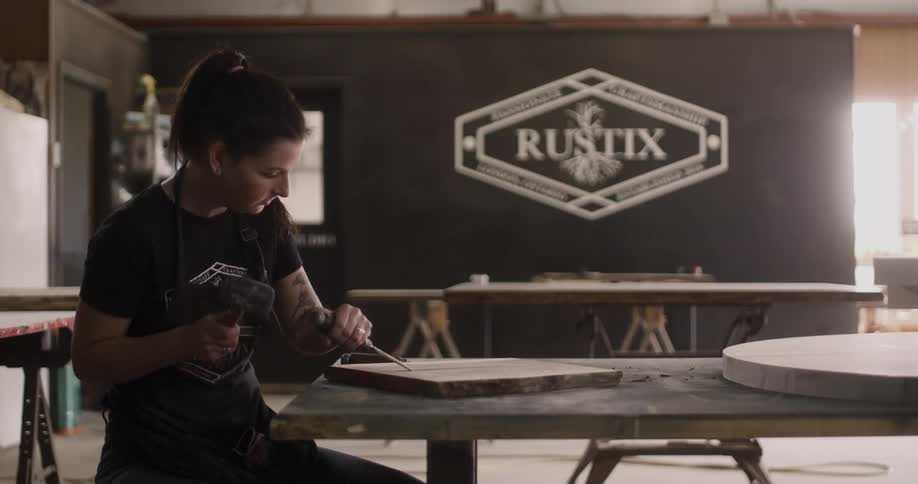 Woman chiseling a slab of wood with a mallet and chisel