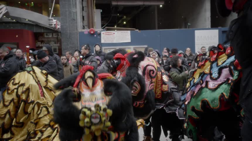 People are playing in dragon costumes with many people surrounding them