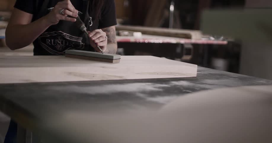 Craftsman hand filing a tool on workshop