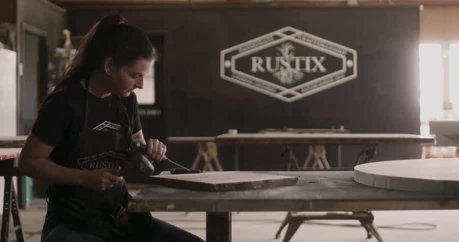 A caucasian craftswoman chiseling a block of wood