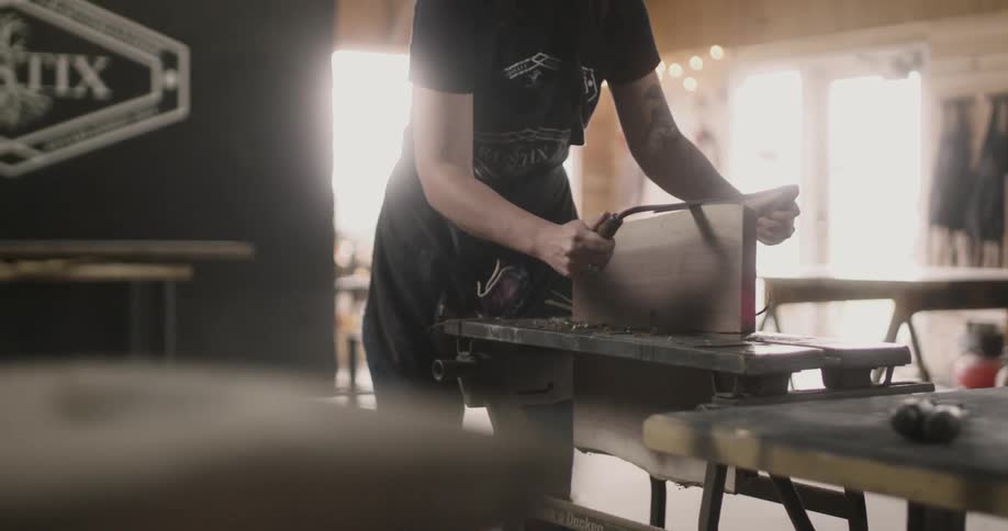 A person saving a piece of wood in a vice