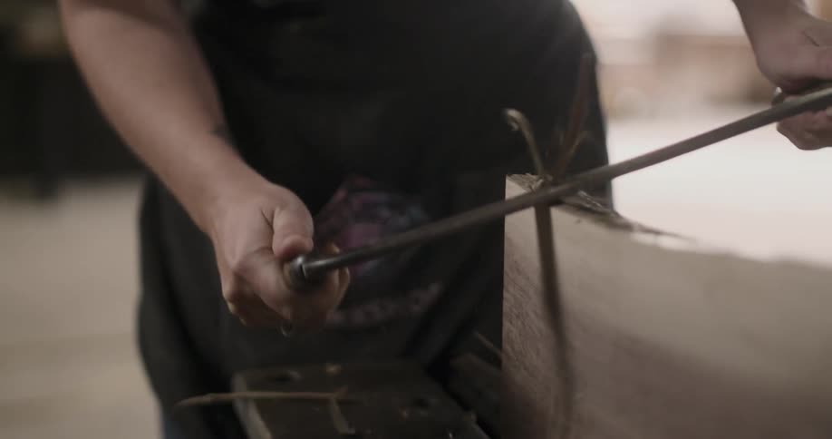 Person shaves wood to form shape