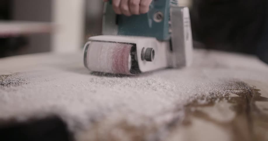 A powered sander being used on a wooden surface