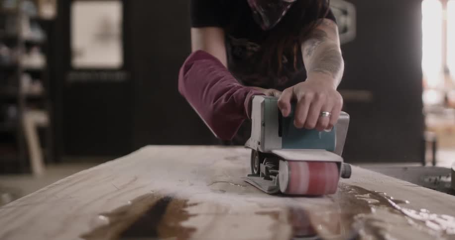 A man sands a piece of wood