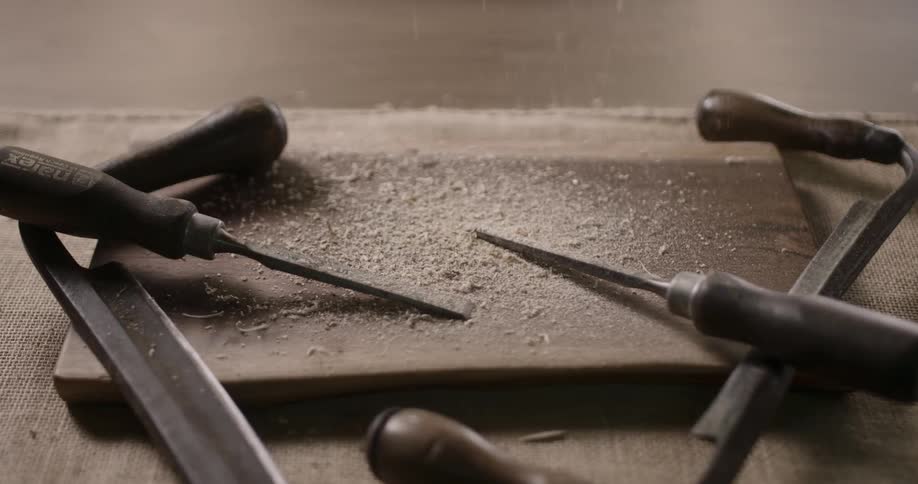 Wood shavings fall onto a surface with tools