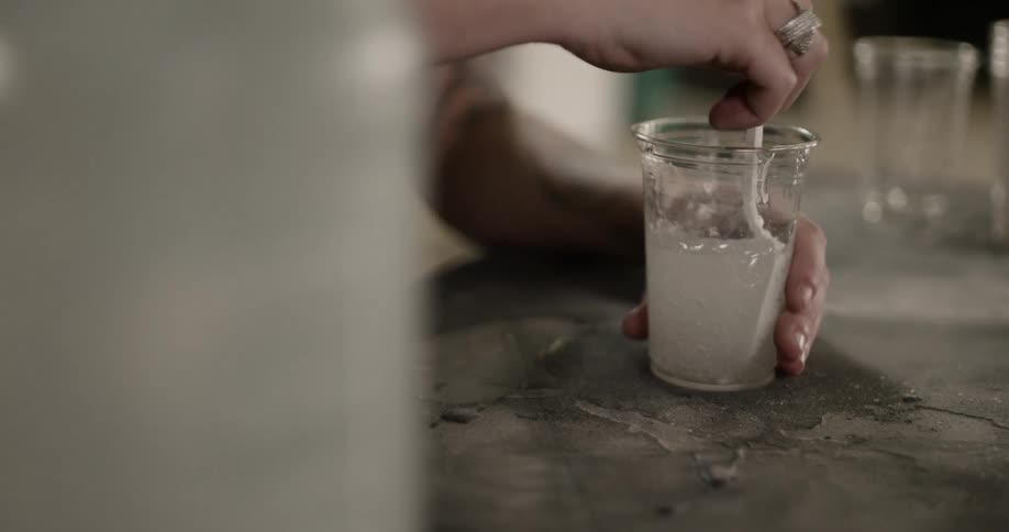 Person stirs thick syrup in a cup