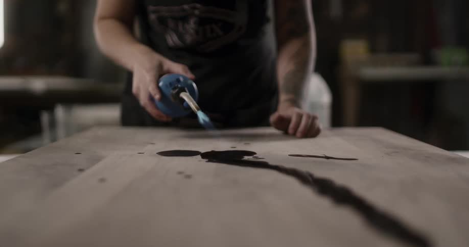 A woman uses a torch on a table