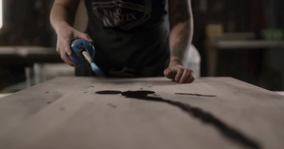 A person is moving a blue torch back and forth across a board