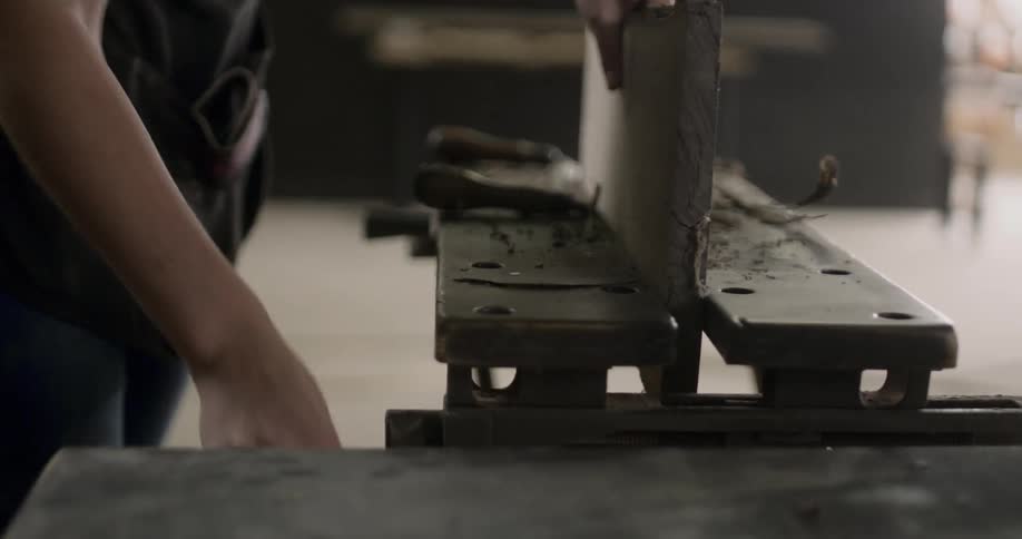 A person is placing a piece of wood into a clam in order to hold it in place while they work on it