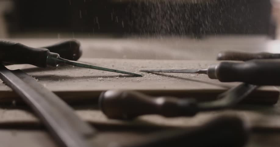 Sawdust falls on tools sitting on a wood table