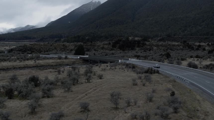 Skyline view of a grassy area mountains and a car driving on the street