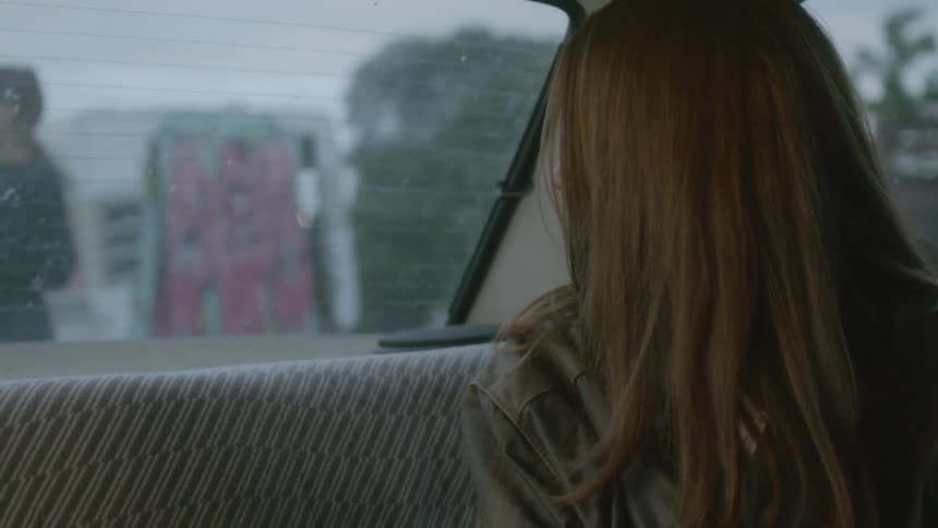 A woman turns to look out the back window of the car