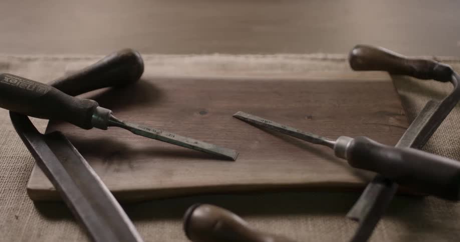 Antique woodworking hand tools sit on a wooden board