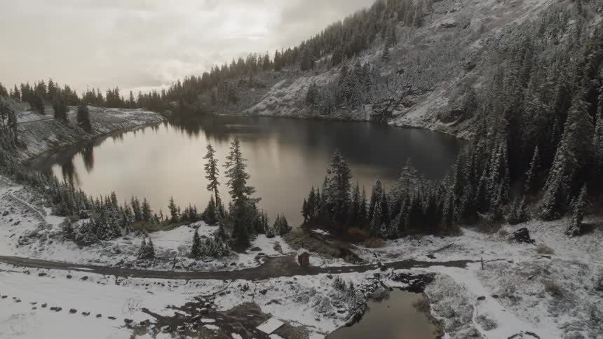 A view of a small lake surrounded by snowy mountains on a clear day