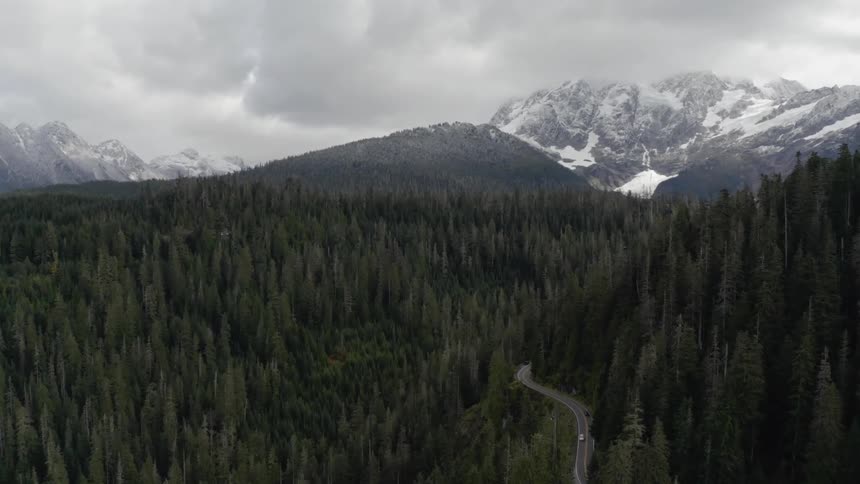 Cars travel along road through dense forest and mountains