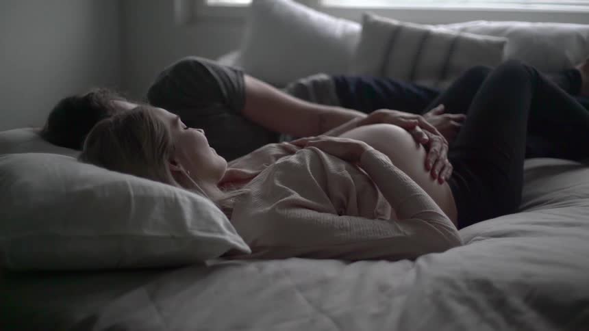 A man is holding a pregnant women on the bed