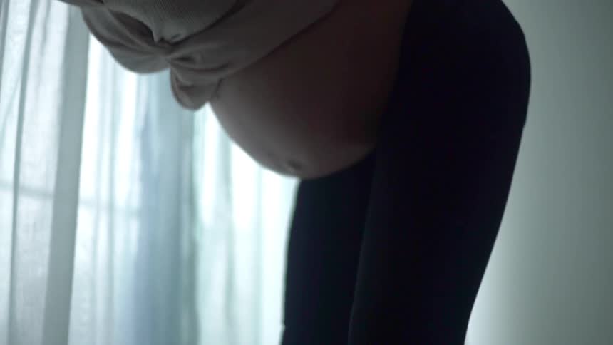 Pregnant woman stands bending over