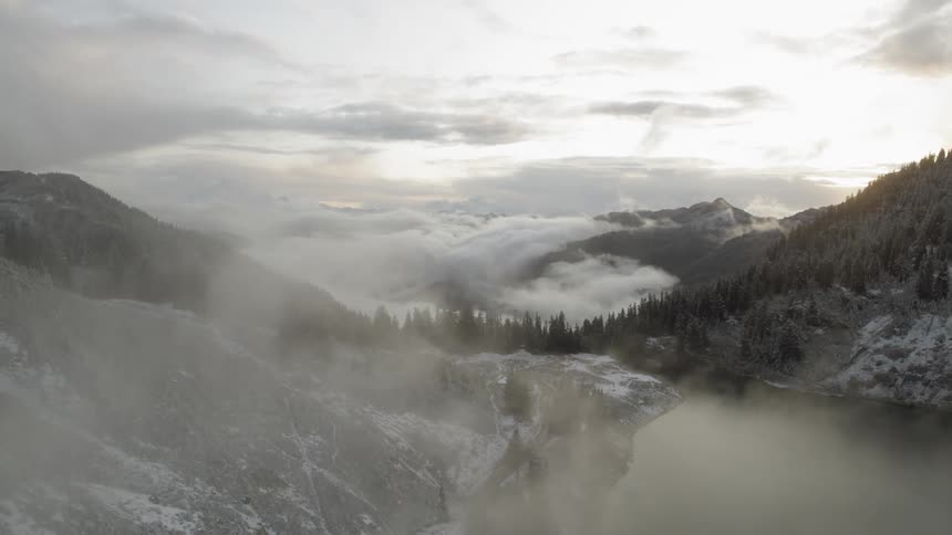 Fog rises above a lake surrounded by mountains