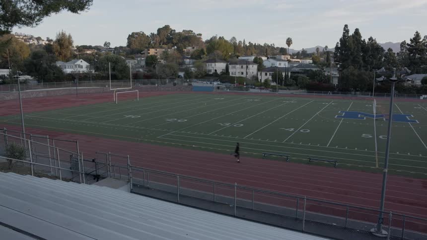 A person running down a track around a football field