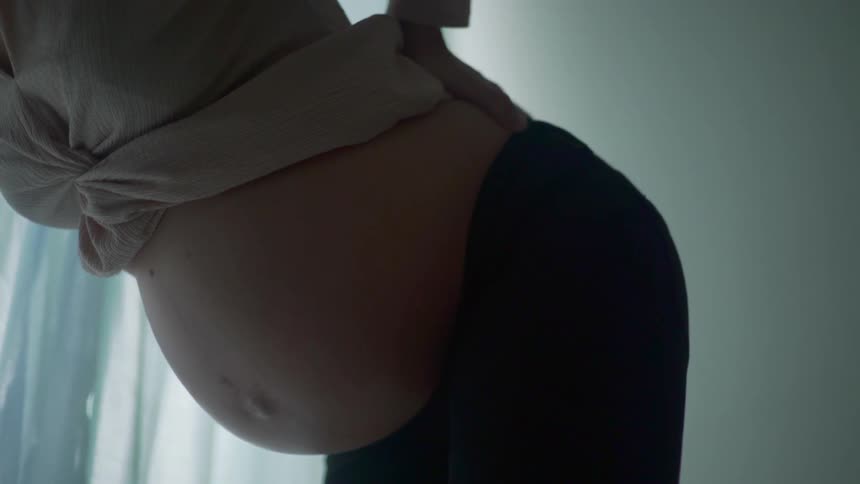 A pregnant woman shows her belly as she stretches