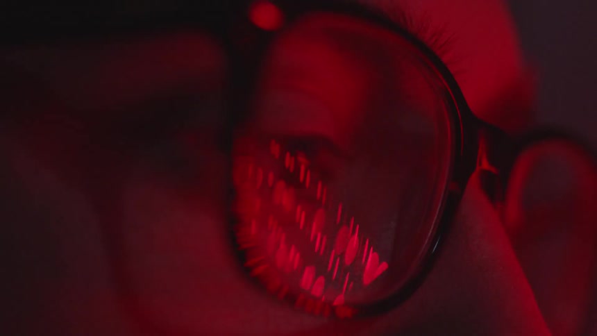 Close up of red lights reflected in man eyeglasses