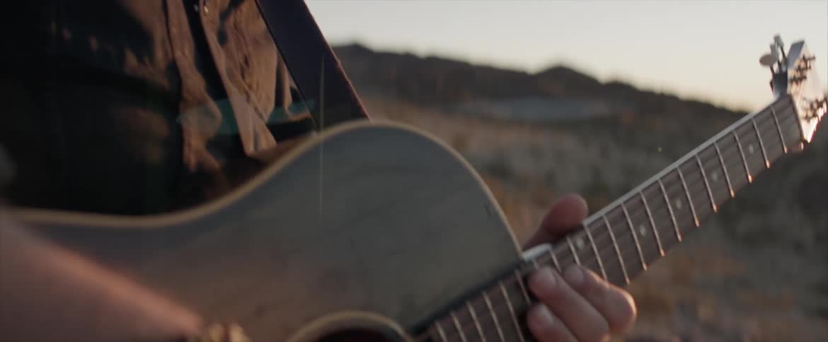 A person standing the desert playing the guitar