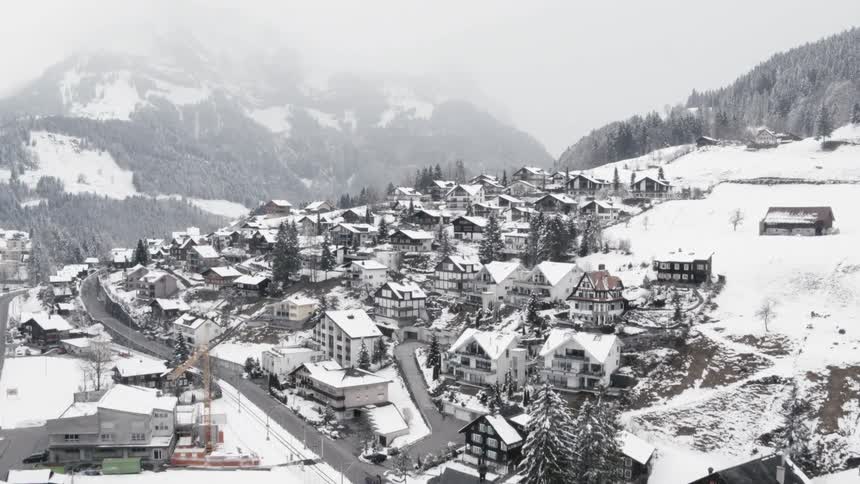 Snow covered village sits near the tree covered mountain