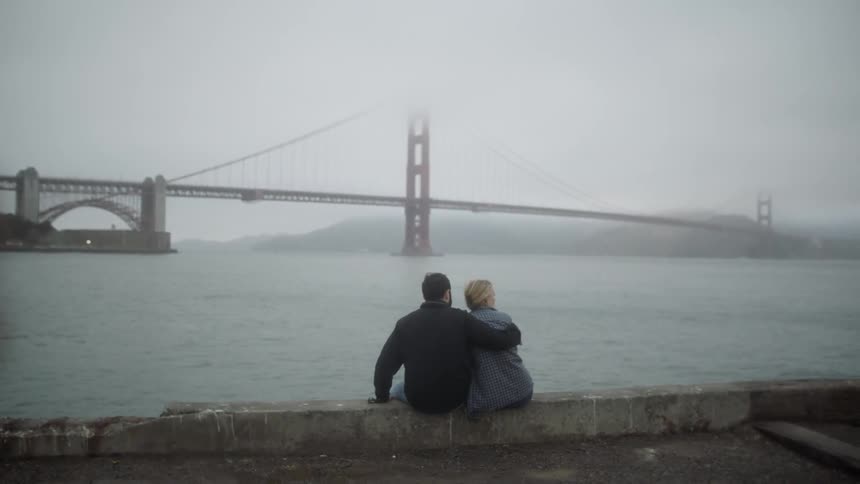 A couple sits on an embankment made of conrete slabs