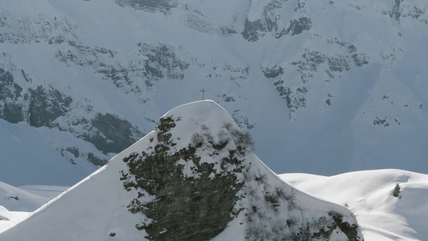 A cross on the peak of a snowy mountain ridge