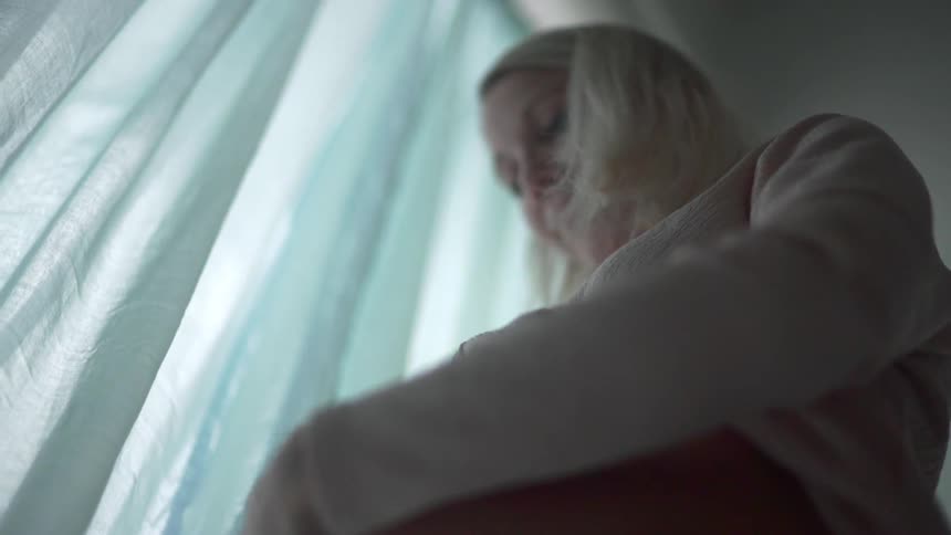 A blonde white pregnant woman rubs her swollen belly