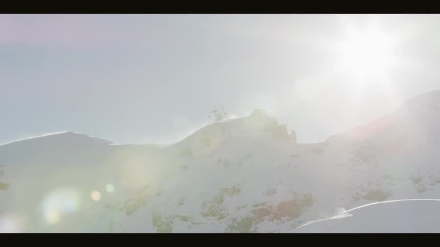 The sun shines high above a mountain range