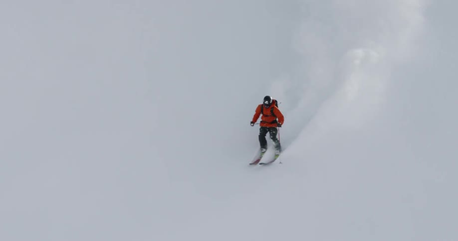 A person skis down a snow covered mountainside