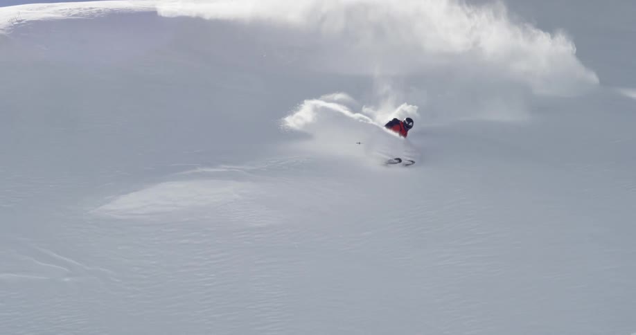 A man skis down a slope and falls backwards