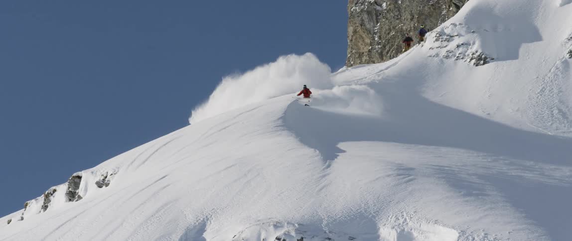 A person skis down a steep snowy mountain side