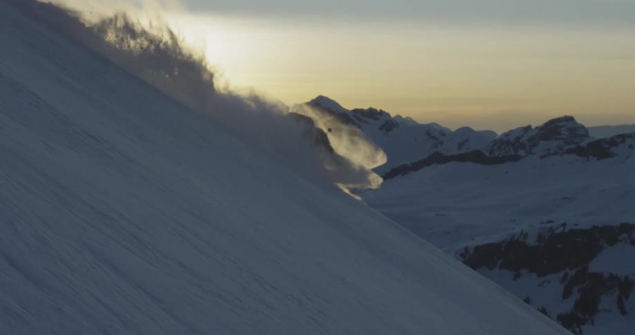 A person skiing falls down the cliff and becomes invisible in a cloud of snow