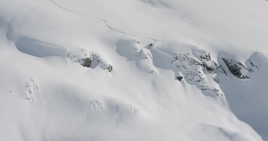 A person skiing down a large mountain covered in snow