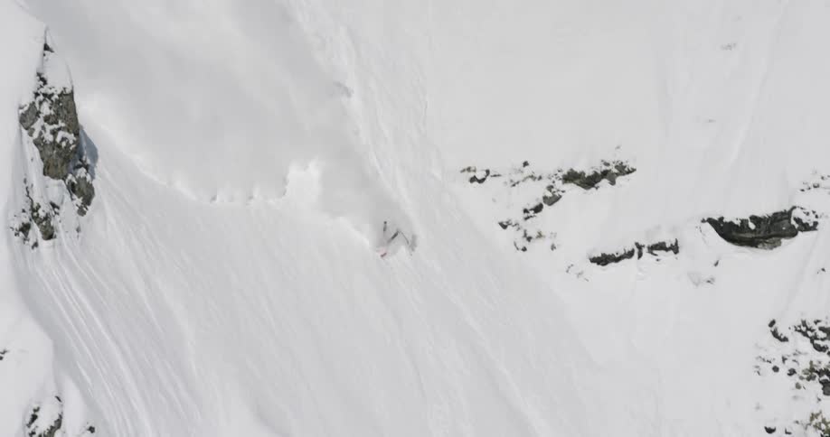 A skier loses control descending a steep vertical slope and flips a few times in the snow