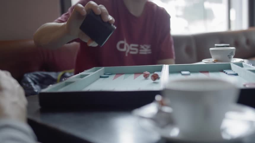 A boy shakes a dice cup while playing backgammon