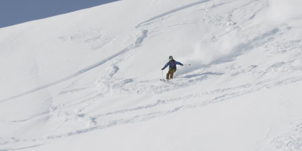 A skier zooms down a mountain slope covered in snow