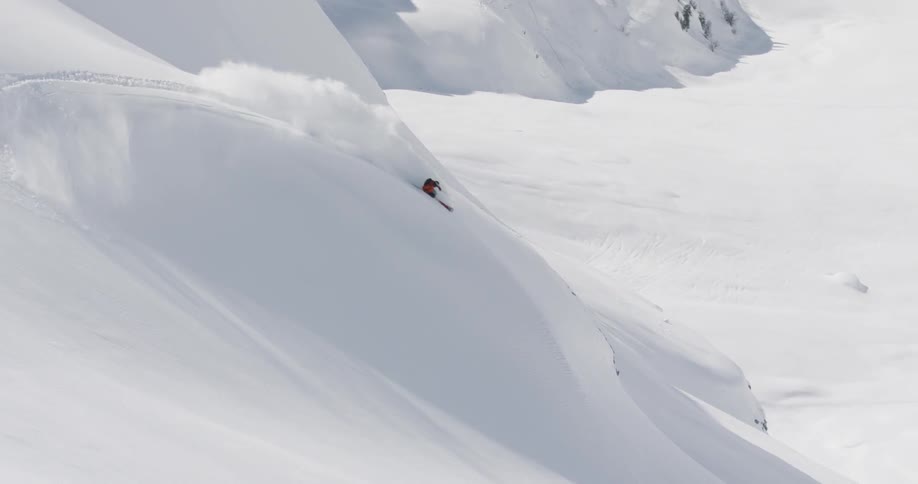 A skier snowboards down a snow covered mountainside