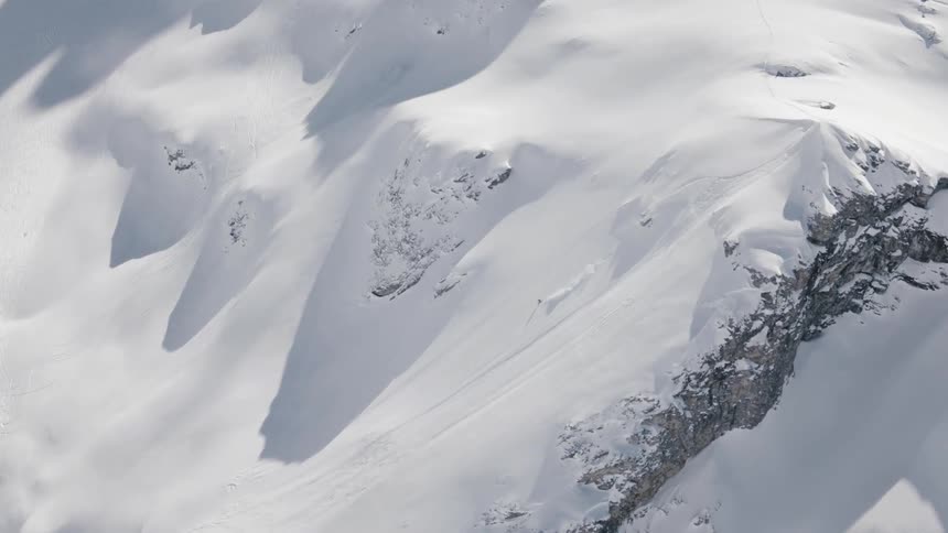 A skier races down a snow covered mountain slope