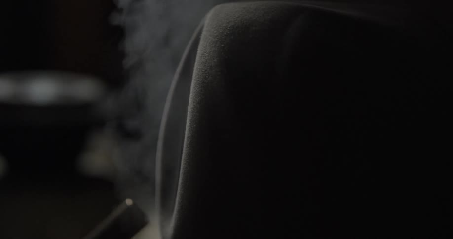 A hat is turned and tilted as it is steam cleaned