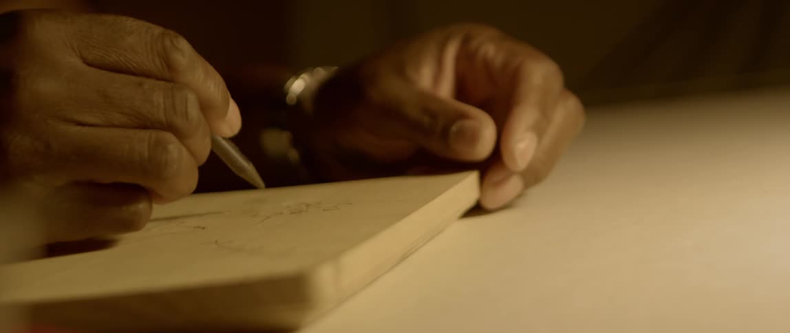 A black person writes on a block of wood
