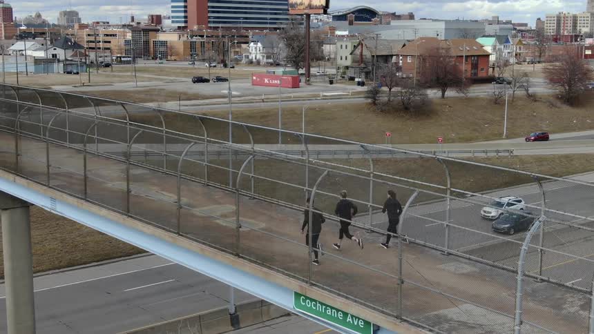 Runners running across freeway overpass in the city