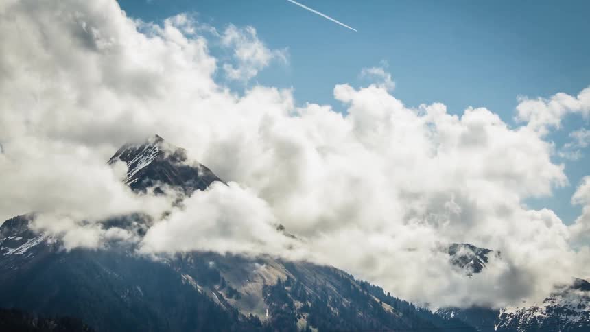Clouds swirl around a mountain peak