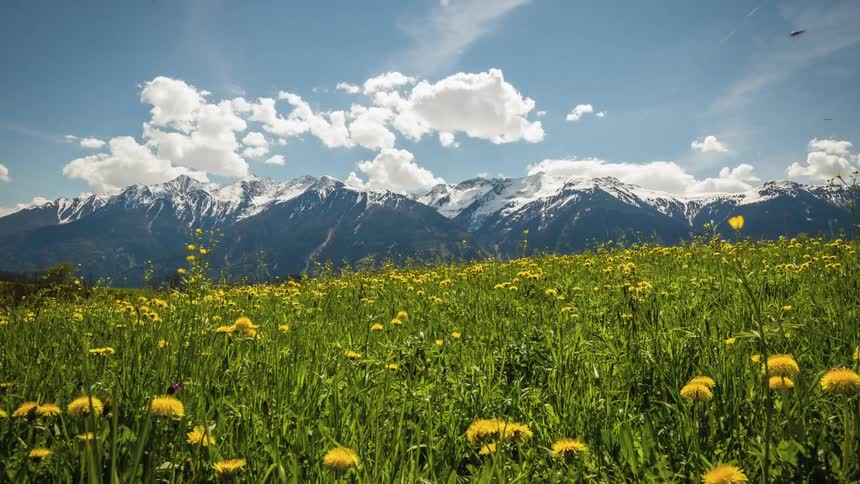 Puffy clouds roll over a mountain top and grasslands