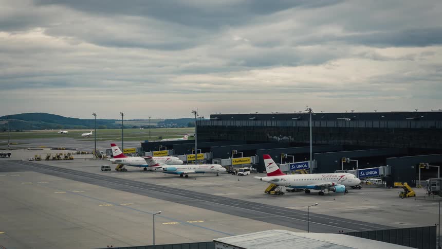 Busy airport with planes taxing to terminal and vehicles loading and unloading
