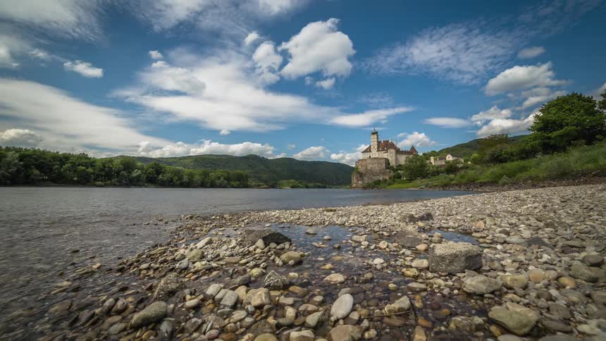 A castle at the end of a river surrounded by green forests