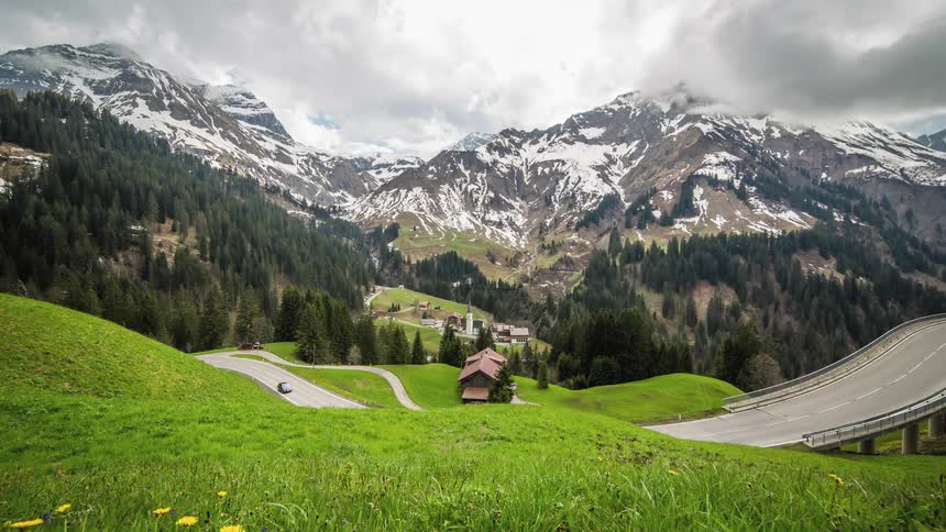 A road going through a countryside with snowy mountains the distance